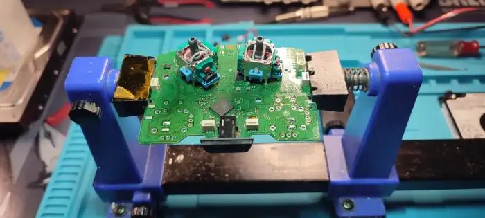Reparación de joystick con placa expuesta en soporte de trabajo